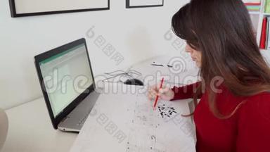 设计工程师坐在她办公室的<strong>办公桌</strong>前，在笔记本电脑上打字，在她的<strong>办公桌</strong>上放蓝图